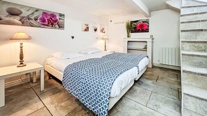 Un dormitorio con cama, mesitas de noche, chimenea y una escalera.