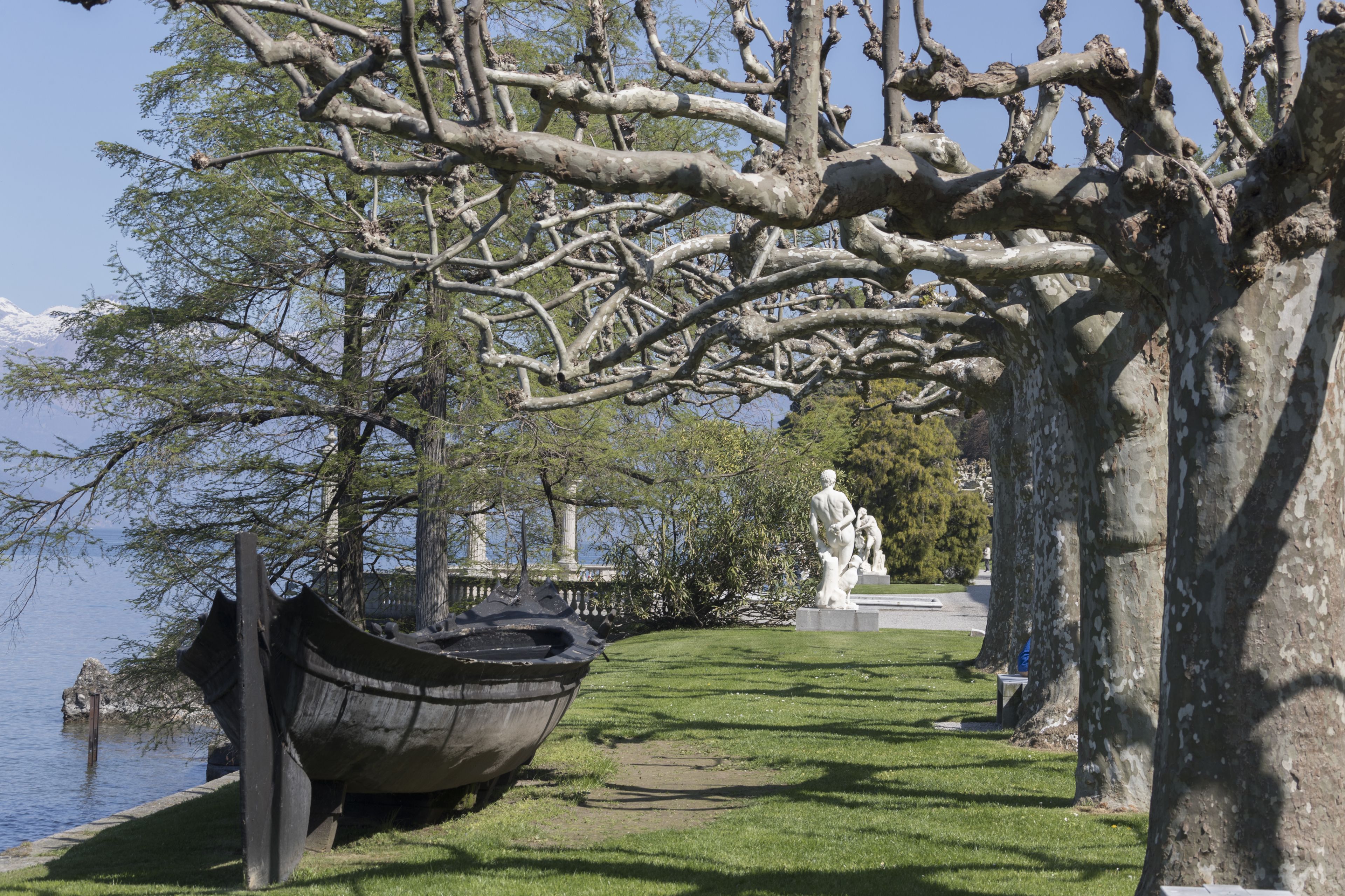 En park med en båtskulptur, en staty och ett stort träd.