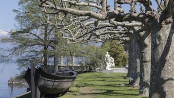 Un parc agrémenté d’une sculpture en forme de bateau, d’une statue et d’un grand arbre.