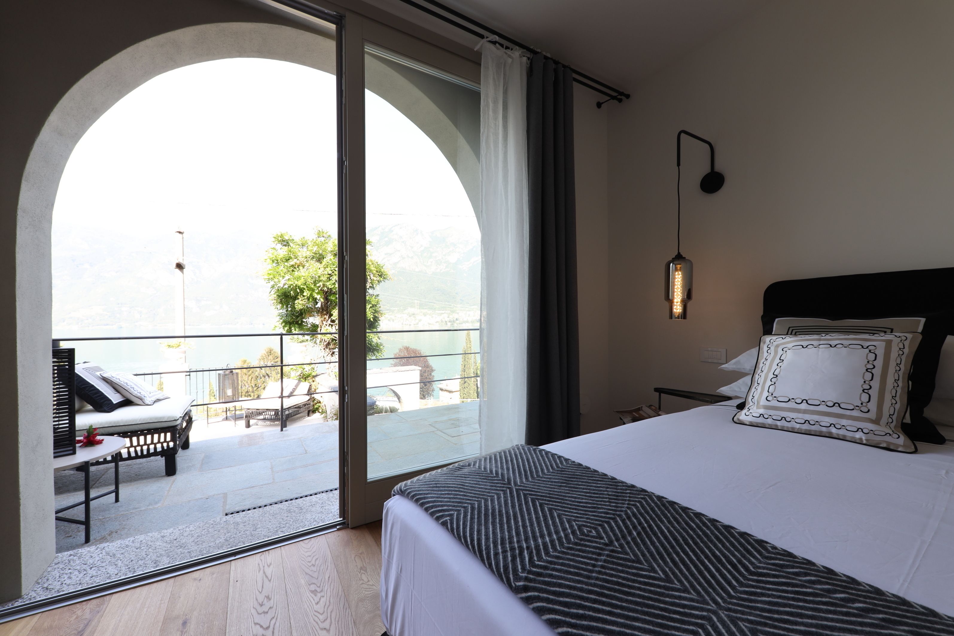 Habitación de hotel con una cama grande, vistas a un balcón y un área de descanso con una mesa y sillas.