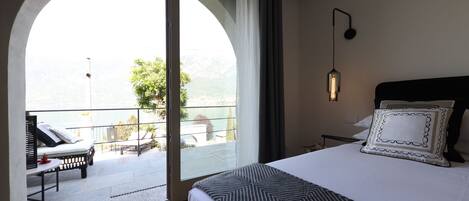 Habitación de hotel con una cama grande, vistas a un balcón y un área de descanso con una mesa y sillas.