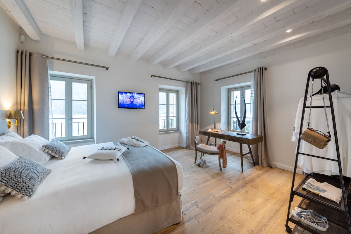A bedroom with a bed, a desk, a chair, a TV, and a shoe rack.