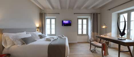 A bedroom with a bed, a desk, a chair, and a TV on the wall.