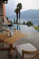 Puisesta pöydästä löytyy kynttilä, pehmustettu tuoli, ja näköala avautuu uima-altaalle, jonka taustalla kohoavat palmut ja vuoret.