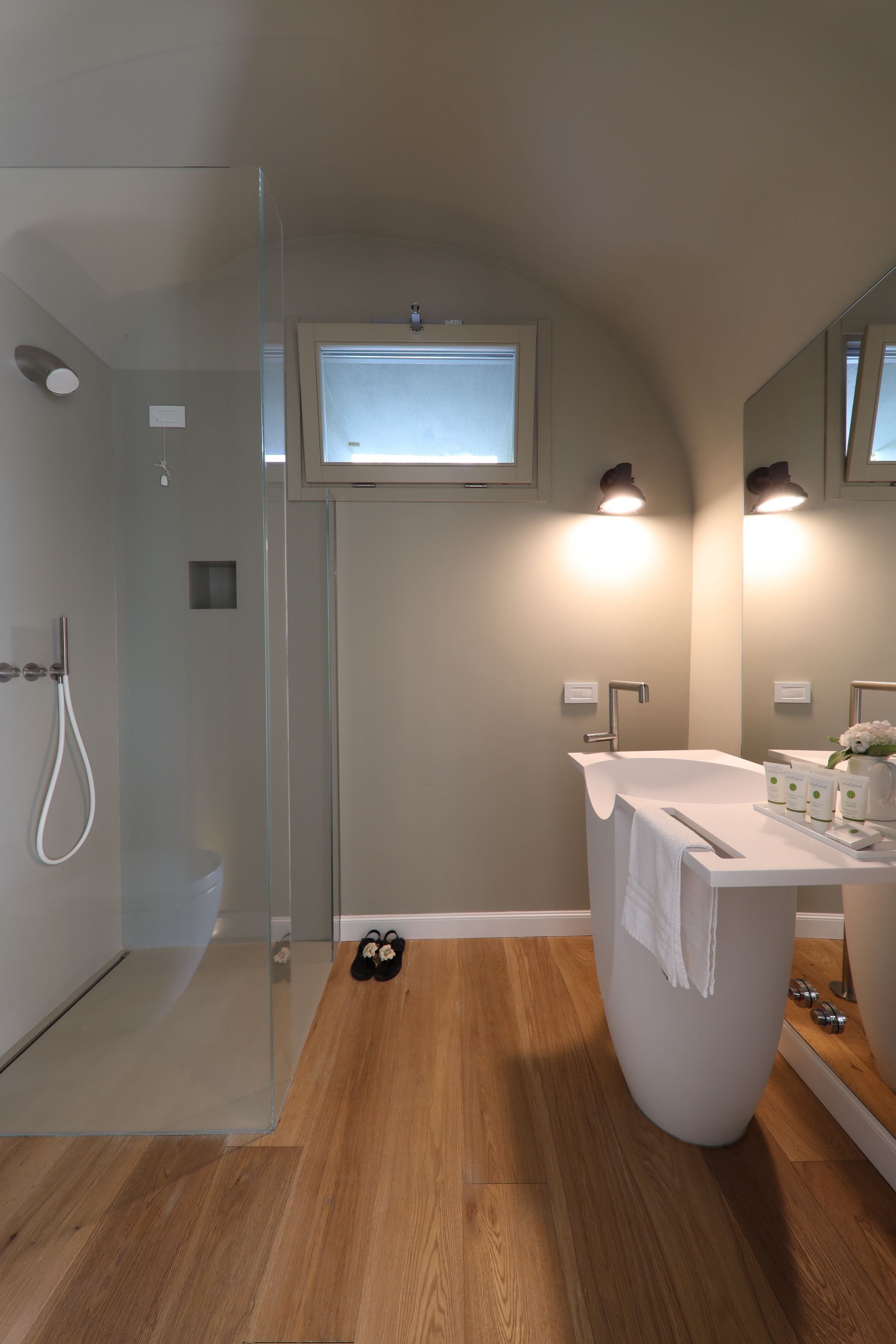 A modern bathroom with a glass-enclosed shower, a freestanding bathtub, and a vanity with a mirror.