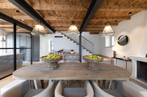 Un comedor con una mesa de madera, cestas de mimbre llenas de fruta e iluminación colgante moderna.