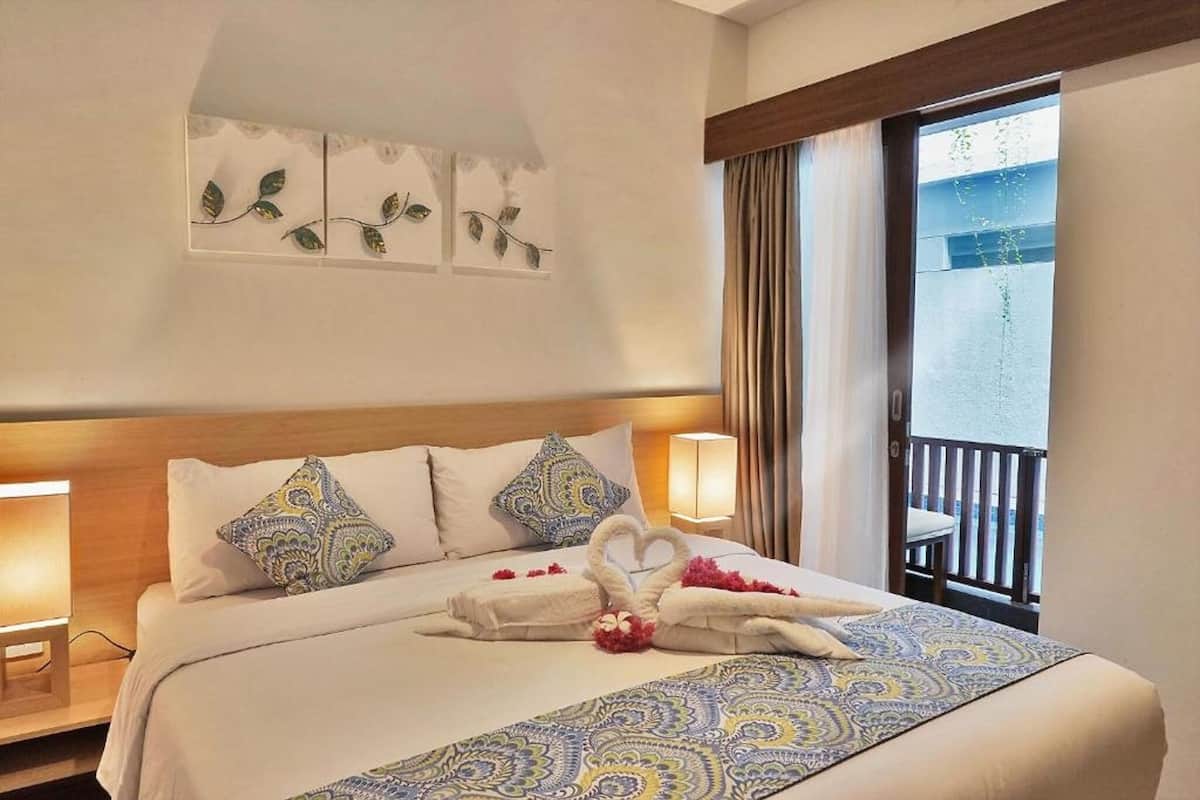 Ein Hotelzimmer mit einem Bett, zwei Nachttischlampen, einer Wanddekoration und einem Balkon mit Vorhängen.