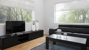 A modern living room with a large flat-screen TV, black sofa, and a coffee table. - Blue Luxury Apartments (Reykjavik)