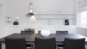 A modern kitchen with white cabinetry, a stainless steel range hood, and a coffee machine. - Blue Luxury Apartments (Reykjavik)