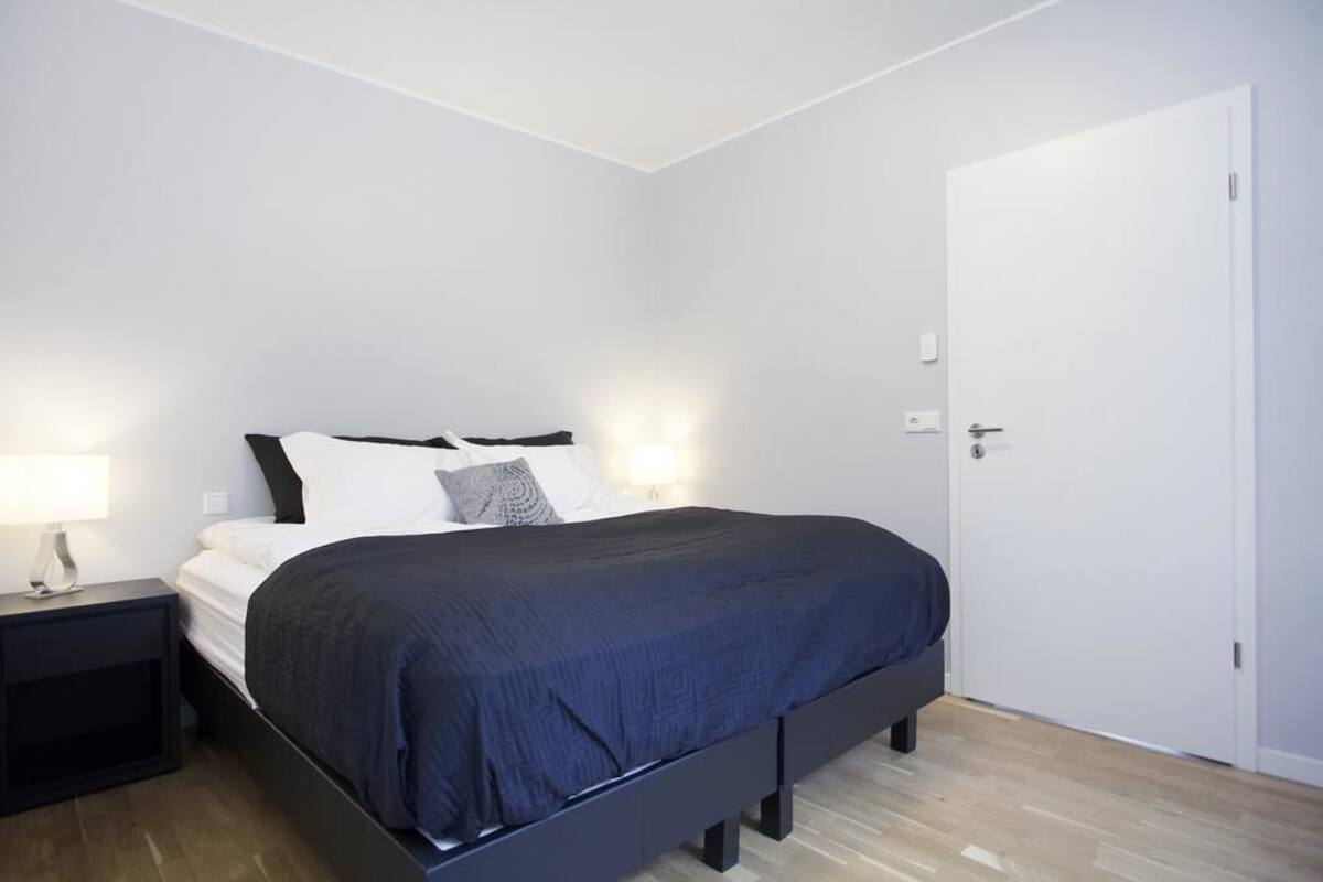 Une chambre à coucher avec un lit, une table de chevet et une porte blanche.