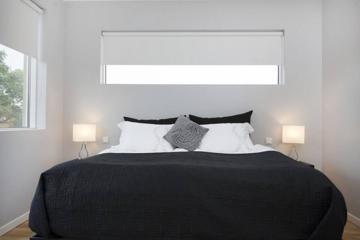 Une chambre moderne avec un grand lit, deux lampes de chevet et une fenêtre située au-dessus du lit.