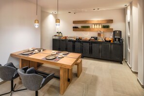 Une cuisine moderne avec une table à manger en bois, des chaises et une machine à café.