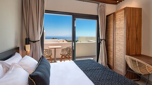 Habitación de hotel con cama, escritorio, silla y vista al mar.