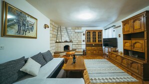 Una sala de estar con sofá, chimenea, armarios de madera y televisión.