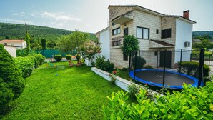 Una casa de dos pisos con un césped cuidado y un trampolín en el jardín trasero.