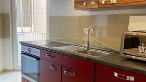 A modern kitchen with a built-in oven, stainless steel sink, and wooden cabinets. - City Pension Bremerhaven (Bremerhaven)