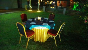 Un comedor al aire libre con una mesa redonda dispuesta para cuatro personas, rodeada de sillas con cojines rojos.