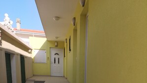 En smal hall med en trappa i beige som leder upp till en vit dörr.