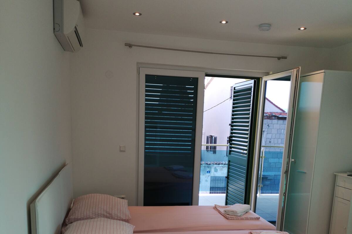 A bedroom with a double bed, a bedside table, a wardrobe, and a sliding glass door leading to a balcony.