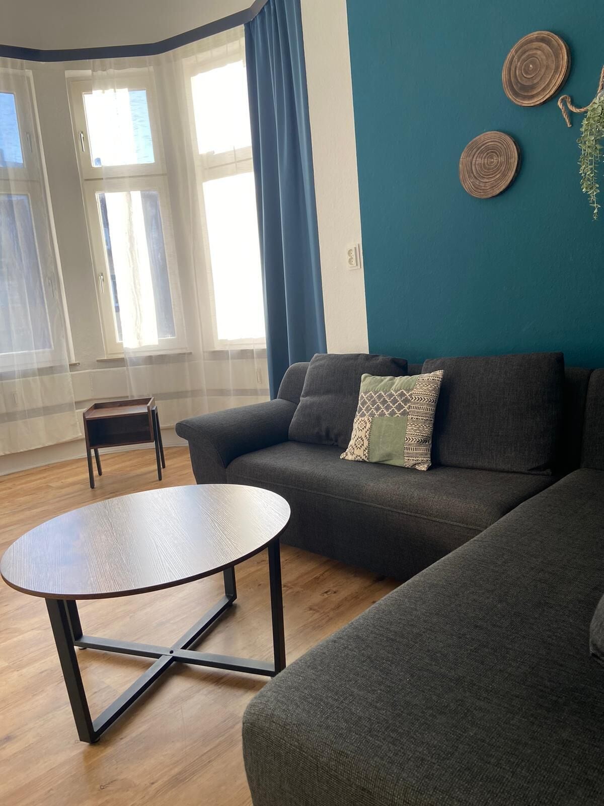 Un salon moderne avec un canapé gris, une petite table d’appoint et une table basse ronde.