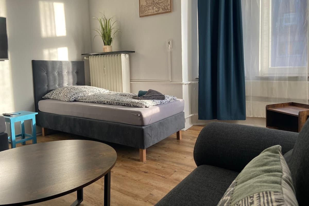 Une chambre à coucher moderne avec un lit, une petite table, un canapé et une plante en pot.