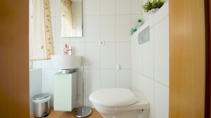 Une petite salle de bain avec des toilettes, un lavabo et une poubelle.