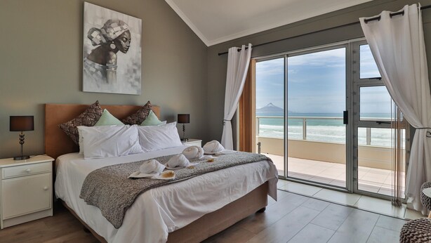 Una camera da letto con un letto, un comodino, una lampada, un quadro e vista sull'oceano.