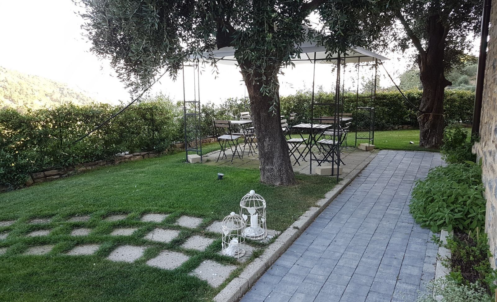 Un jardín con un camino empedrado, un pabellón y mobiliario para el aire libre.