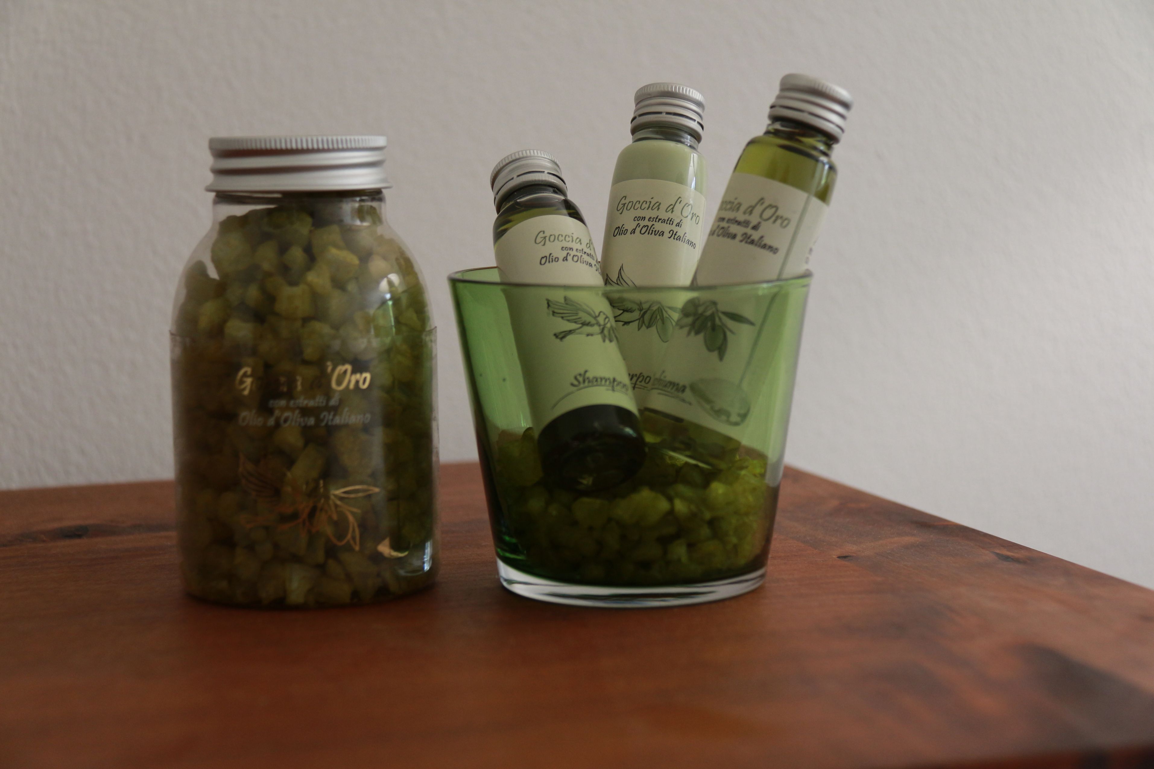 Un bocal rempli d’olives conservées et un récipient en verre contenant des bouteilles d’huile d’olive.