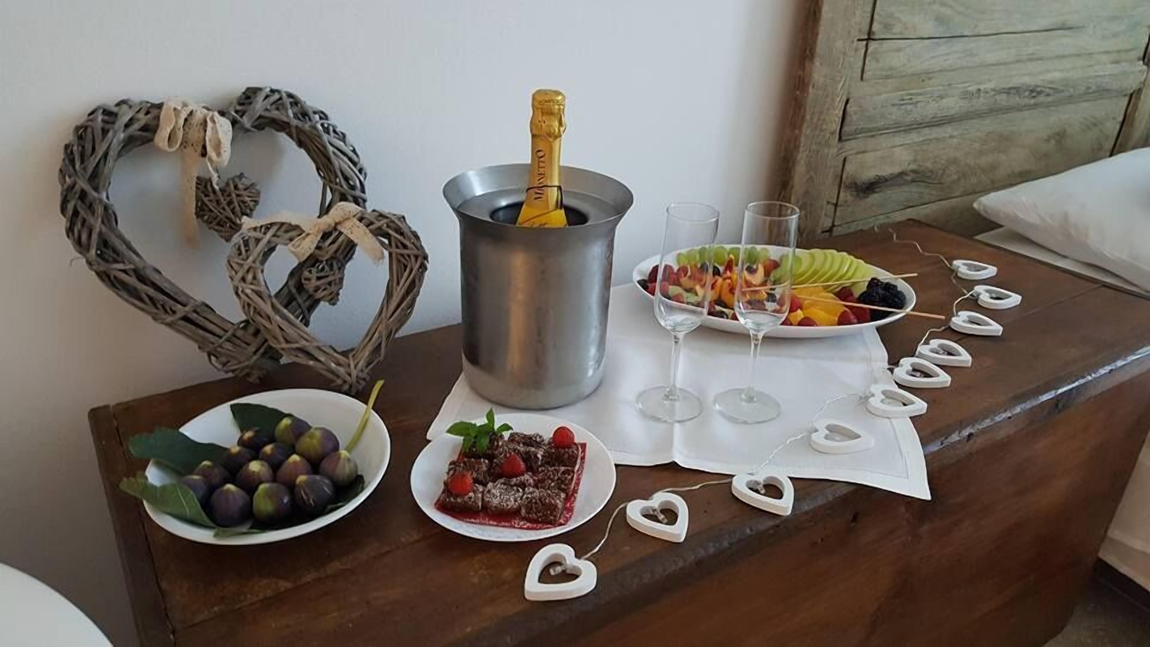 Un tavolo con una bottiglia di champagne, spiedini di frutta e decorazioni a forma di cuore.