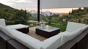 Un espace extérieur aménagé avec des meubles en osier et une table à plateau de verre, offrant une vue sur un paysage pittoresque.