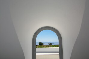 An arched window with a view of the sea and greenery. - Philosophia Luxury Villa (Santorini)