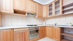 Een keuken met houten kastjes, een gasfornuis, een oven en een spoelbak.