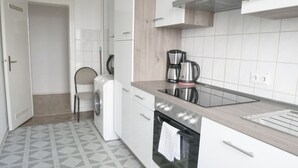 Una cocina moderna con horno integrado, cafetera y lavadora.