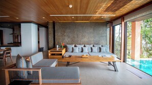 A modern living room with a wooden ceiling, a large sofa set, a coffee table, and a view of a swimming pool. - 4BR Residence Pool Villa Ocean View - Sri panwa (G11) (Phuket)