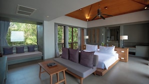 A modern hotel room with a sofa, a bed, a desk, and large windows offering a view of greenery. - 4BR Residence Pool Villa Ocean View - Sri panwa (G11) (Phuket)