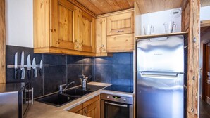 Une cuisine moderne avec des meubles en bois, un réfrigérateur en acier inoxydable et un four encastré.