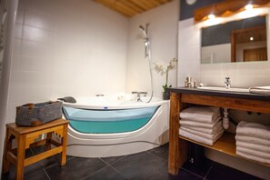A modern bathroom with a freestanding bathtub, a wooden stool, a sink with a mirror, and a shelf with towels. - galta, this warm apartment can accommodate up to 12 people, ideal for large families or stays with friends. (Valloire)