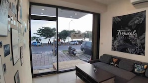 A hotel lobby with a sofa, a coffee table, and a large window with a view of parked cars and a sign reading "No Vacancy". - Hearty Homestay (Hengchun)