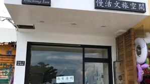 A hotel entrance with a glass door, a wooden bench outside, and a sign indicating a vacancy. - Hearty Homestay (Hengchun)