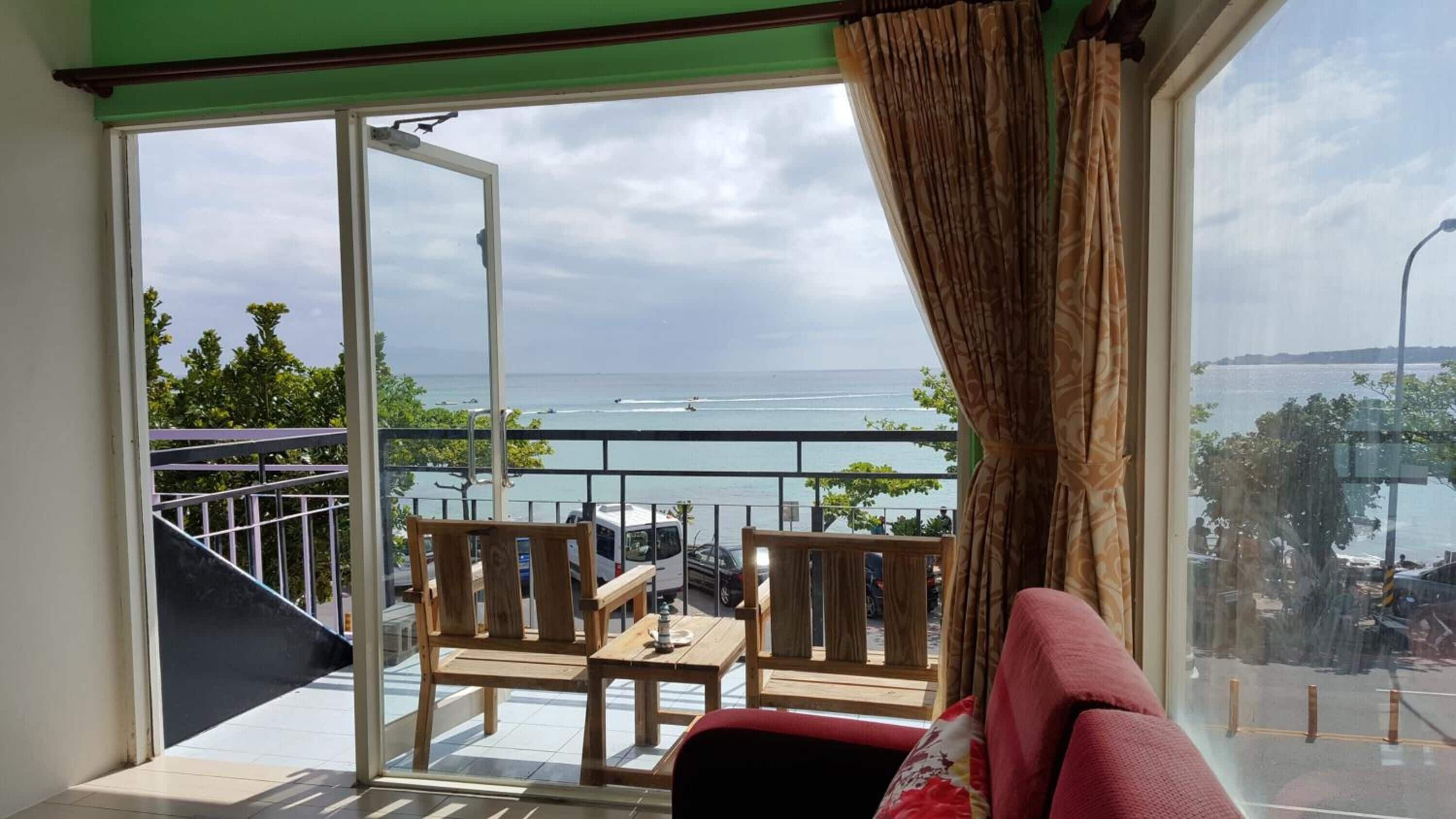 Varanda com vista para o mar, móveis de madeira e porta de correr de vidro.