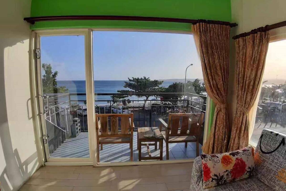 Un balcó amb vistes al mar, una taula de fusta i dues cadires.