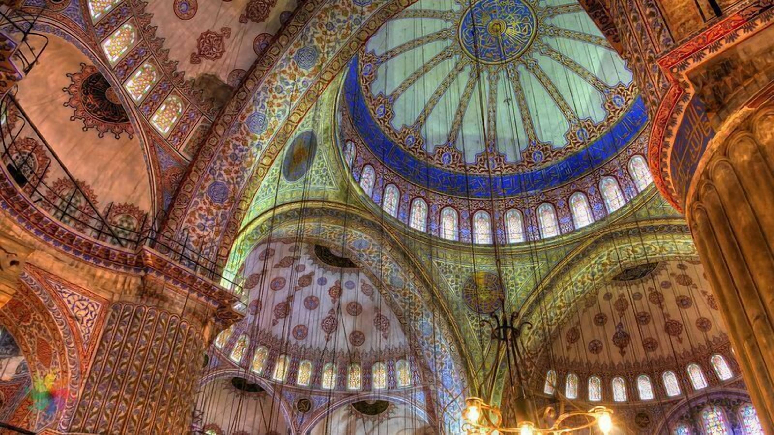 An ornate interior with intricate ceiling designs and stained glass windows.
