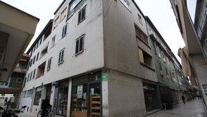 Un immeuble à plusieurs étages, avec un commerce au rez-de-chaussée et plusieurs balcons.