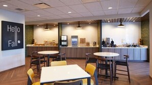 A modern cafe with wooden flooring, round tables, and yellow chairs. - Fairfield Inn & Suites by Marriott Riverside Moreno Valley (Moreno Valley)