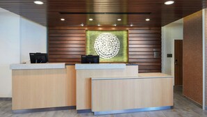 A reception desk with two counters, a decorative wall piece, and a wooden panel design. - Fairfield Inn & Suites by Marriott Riverside Moreno Valley (Moreno Valley)