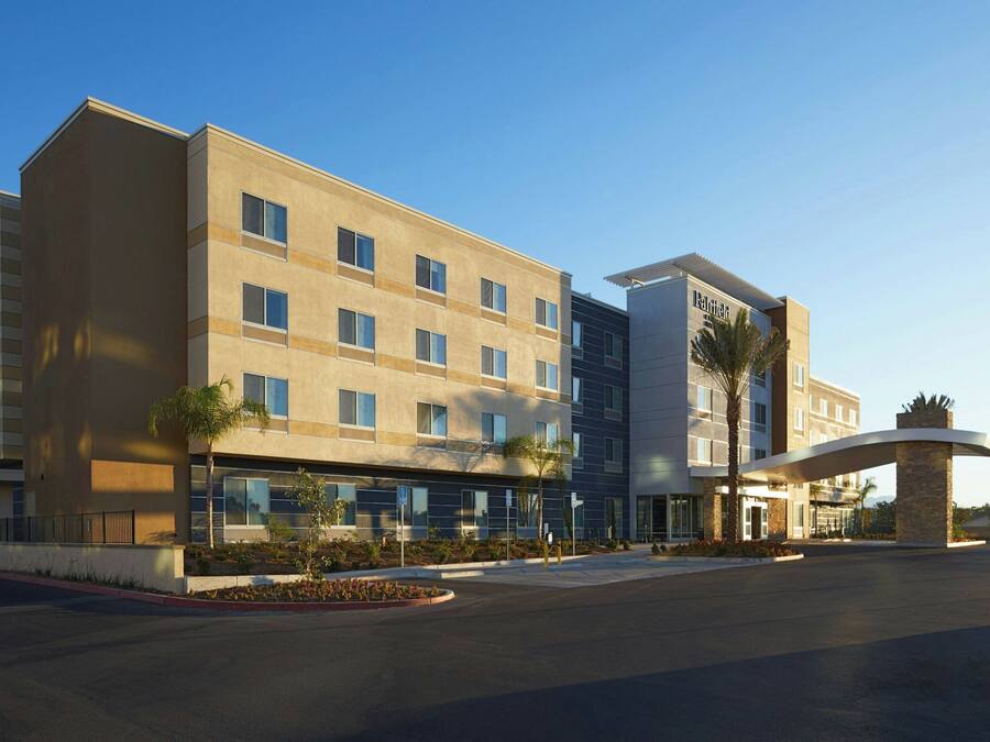 A modern hotel with a flat facade, multiple windows, and a curved entrance canopy.