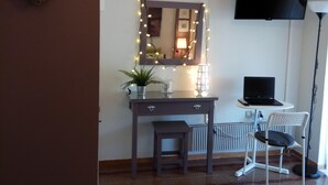 A room with a desk, chair, TV, and a chandelier. - Top Floor Cozy Apartment near Beach (Vari-Voula-Vouliagmeni)