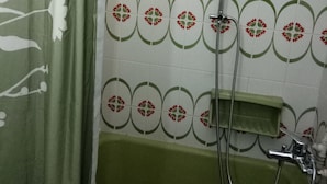 A bathroom with a shower, a green towel rack, and a patterned tile wall. - Top Floor Cozy Apartment near Beach (Vari-Voula-Vouliagmeni)