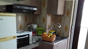 A compact kitchen with a built-in oven, a coffee maker, and a basket of fruit on the counter. - Top Floor Cozy Apartment near Beach (Vari-Voula-Vouliagmeni)